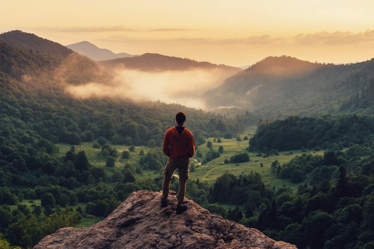 A man standing on a hill overlooking a valley