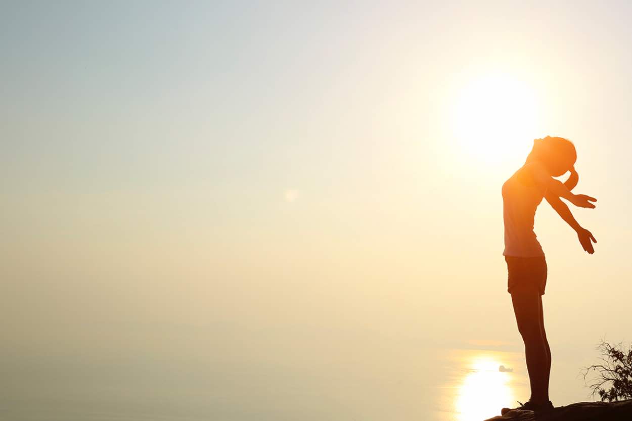 A woman standing on a cliff overlooking the ocean